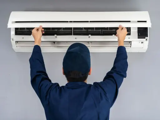 Tecnico apre il pannello di un condizionatore. Il motore esterno del condizionatore è pronto per la manutenzione.