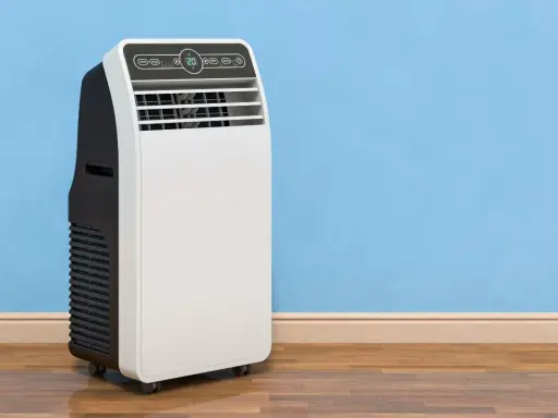 Un condizionatore portatile come funziona: un'unità bianca e nera su ruote, con display digitale, accanto a un muro blu.