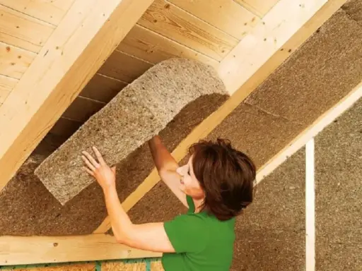 Donna installa pannelli isolanti in fibra di legno, il miglior isolante termico per soffitto, per un tetto efficiente.