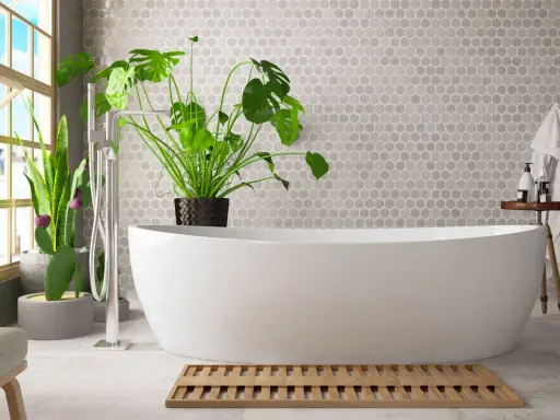 Un bagno umido cosa fare? Una vasca bianca, piante verdi e un tappetino in legno.
