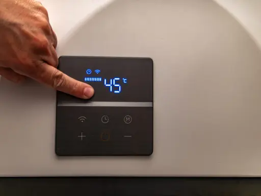 Dito un dito regola la temperatura su una caldaia elettrica a condensazione, impostata a 45°C.
