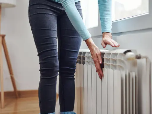 Mani che controllano un termosifone freddo, preoccupazione per il riscaldamento che non funziona.
