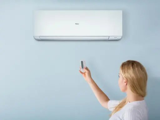 Donna usa il telecomando per regolare il condizionatore Haier. Il significato di "heat condizionatore" è la sua capacità di riscaldare.