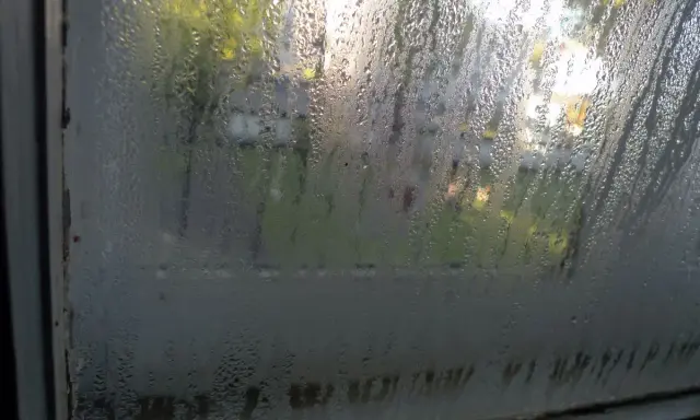 Vetri appannati: un segnale che è ora di capire come misurare umidità in casa. Goccioline d'acqua sul vetro riflettono la luce esterna.