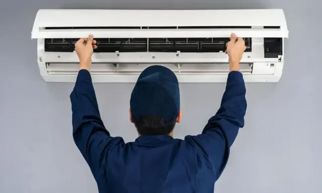 Tecnico apre il pannello di un condizionatore. Il motore esterno del condizionatore è pronto per la manutenzione.