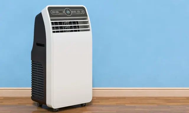 Un condizionatore portatile come funziona: un'unità bianca e nera su ruote, con display digitale, accanto a un muro blu.