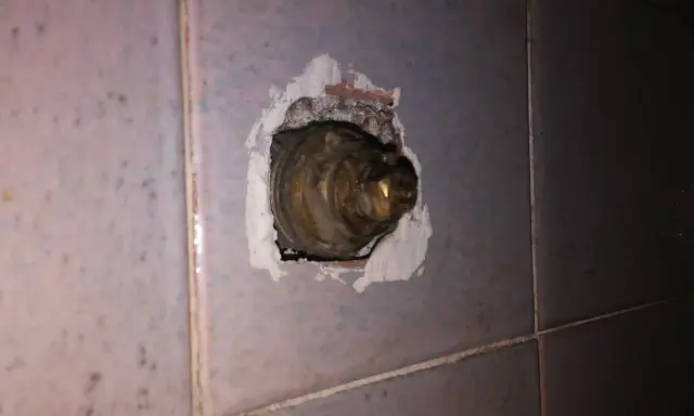 Parte interna di un rubinetto in ottone, incassato nel muro piastrellato. La chiusura del rubinetto acqua senso è necessaria per evitare perdite.