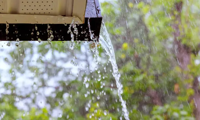 Acqua piovana che scorre da una grondaia, un esempio di impianto recupero acqua piovana pro e contro.