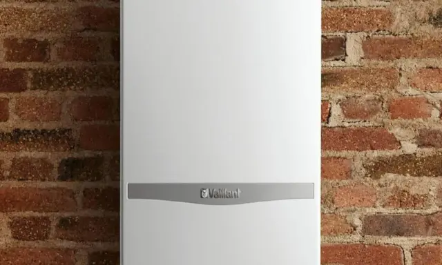 Caldaia Vaillant bianca, con logo, montata su parete in mattoni. Le dimensioni della caldaia sono compatte per adattarsi a spazi ridotti.