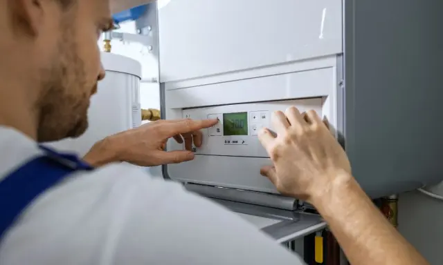 Tecnico che controlla il display della caldaia in blocco, impostando la temperatura.