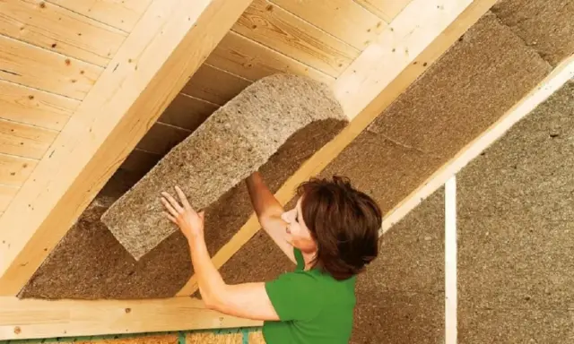 Donna installa pannelli isolanti in fibra di legno, il miglior isolante termico per soffitto, per un tetto efficiente.