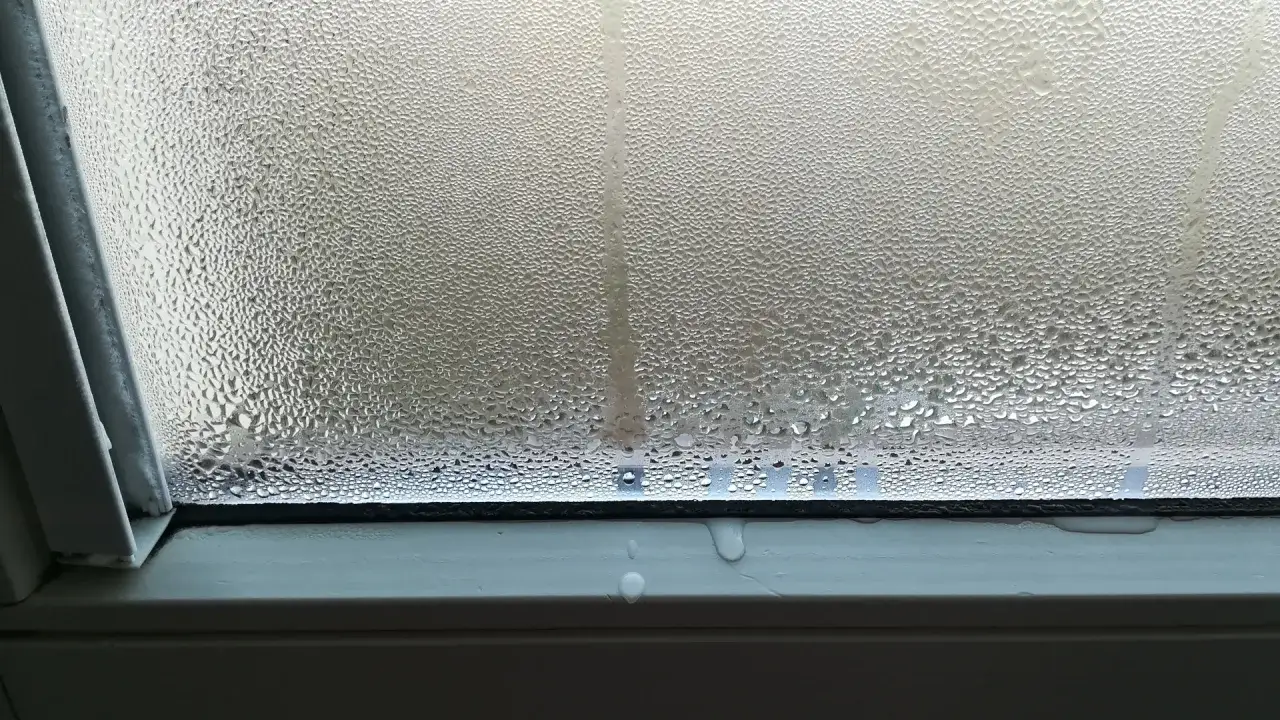 Vetro appannato con goccioline d'acqua, segno di condensa in bagno. L'umidit&agrave; crea un velo opaco sul vetro.