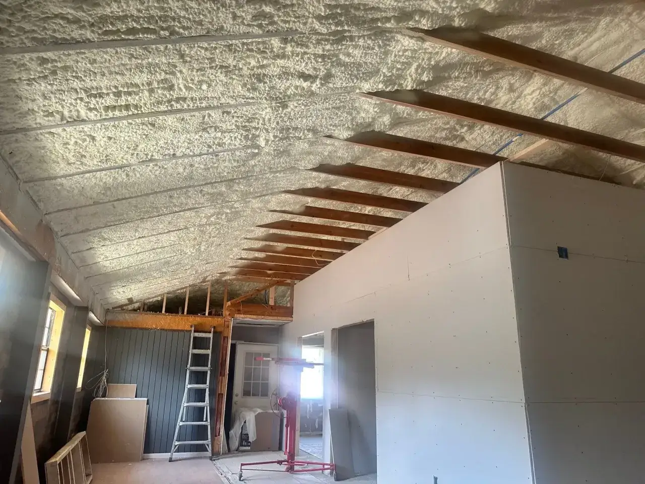 Soffitto con schiuma espansa, il miglior isolante acustico, in una casa in costruzione. Travi in legno a vista.