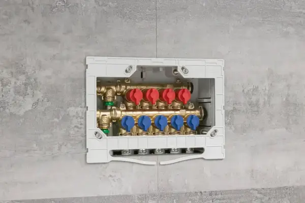 Installazione di collettori idraulici in un box a muro. Questi collettori, con valvole rosse e blu, sono essenziali per la distribuzione dell'acqua.