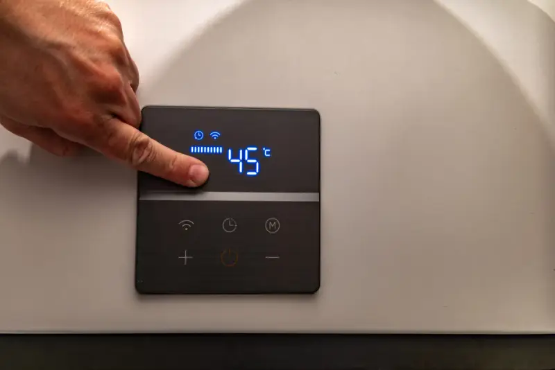Dito un dito regola la temperatura su una caldaia elettrica a condensazione, impostata a 45°C.